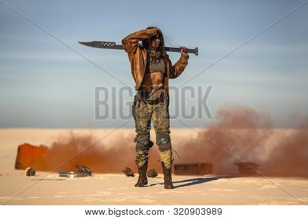 Post-apocalyptic Biker Woman With Weapon Outdoors. Young Slim Girl Warrior In Shabby Clothes Holding