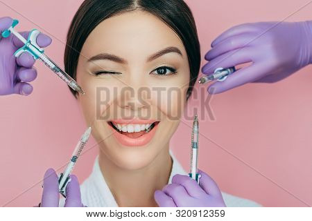 Portrait Of A Beautiful Winking Woman And Many Syringes With Beauty Injections Around Her Face