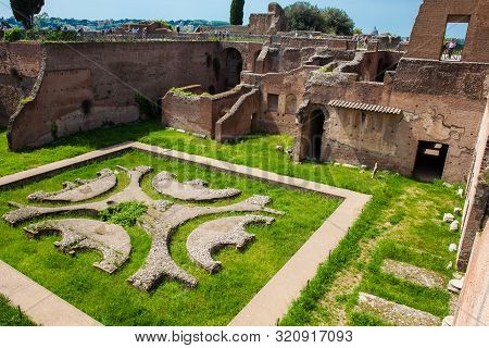 Rome, Italy - April, 2018: Tourists Looking At The Courtyard Garden Of The Ancient Ruins Of The Domu