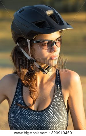 Girl On A Mountain Bike On Offroad, Beautiful Portrait Of A Cyclist At Sunset, Fitness Girl Rides A 