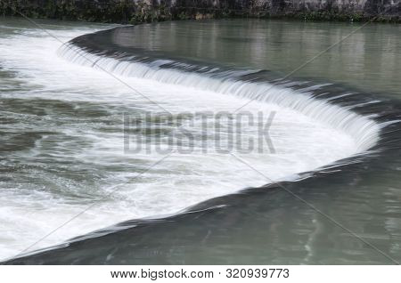 A Curved Manmade Waterfall On The Tuo Jiang River In Fenghuang Ancient Town, Hunan Province China.