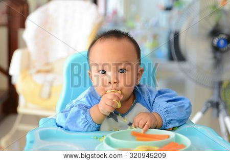 Asian Baby Boy 6 Months Old Eating With Baby Led Weaning (blw) Method, Self-feeding