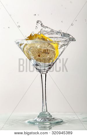 Glass Of Water, Lemon And Watersplashes On A Black Studio Background