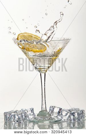Glass Of Water, Lemon And Watersplashes On A Black Studio Background