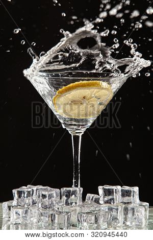 Glass Of Water, Lemon And Watersplashes On A Black Studio Background