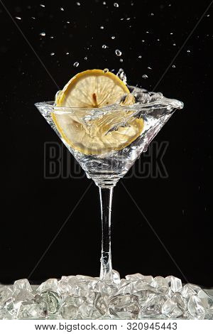 Glass Of Water, Lemon And Watersplashes On A Black Studio Background
