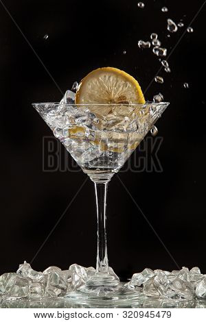 Glass Of Water, Lemon And Watersplashes On A Black Studio Background