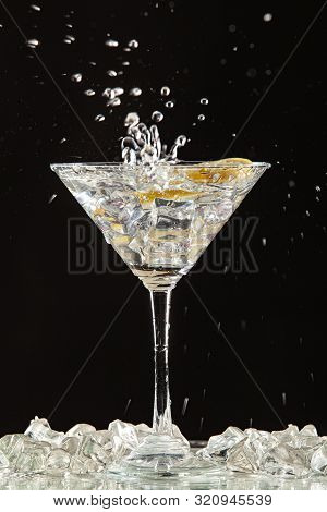 Glass Of Water, Lemon And Watersplashes On A Black Studio Background