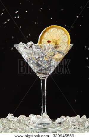 Glass Of Water, Lemon And Watersplashes On A Black Studio Background