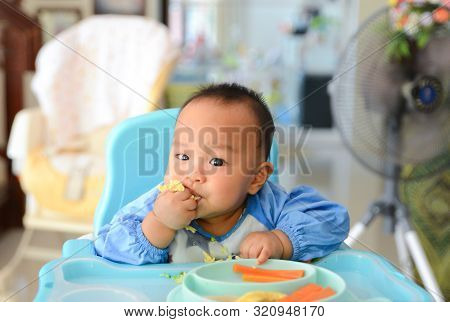 Asian Baby Boy 6 Months Old Eating With Baby Led Weaning (blw) Method, Self-feeding