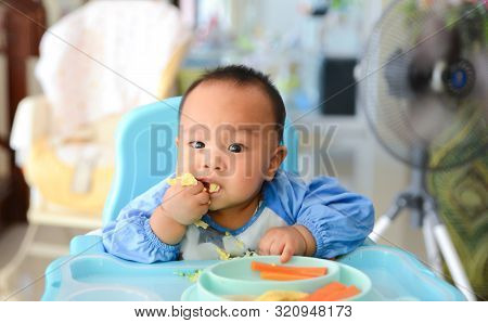 Asian Baby Boy 6 Months Old Eating With Baby Led Weaning (blw) Method, Self-feeding