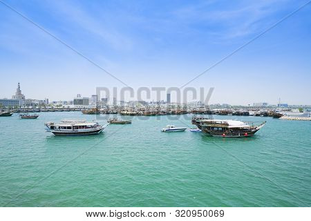 Boats In  Harbor Doha With Turquoise Persian Gulf Water With Old Town Skyline Behind