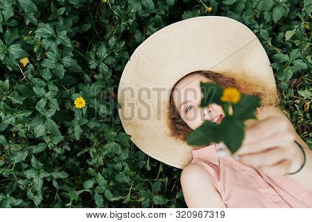 Pretty Young Wman With Beautiful Blue Eyes Lying On Grass, Looking At Camera And Outstretching Hands