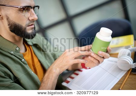 Bearded Handsome Man In Glasses Reading About Vitamins