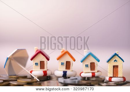 Home Insurance Concept. House Model In Lifebuoys On Coins Stack. Securing Large Value Of Home By App