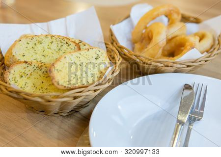 Garlic Bread And Onion Ring In The Basket On A Wooden Desk