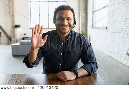 Friendly And Helpful Hindoo Man Wearing Headset Device And Smart Casual Shirt Looks At The Camera An