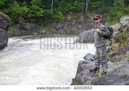 Tramp v maskovací oděv na skalnatém břehu horské řeky. Rusko. Primorskiy kray.