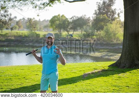 Portrait Of Happy Smilin Golfer Hitting Golf Shot With Club On Course.