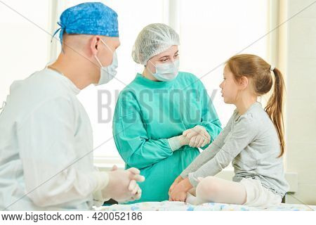 Male surgeon and female nurce explaining a surgery to a child patient