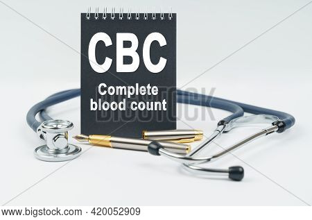Medicine And Health Concept. On A White Background Lies A Stethoscope, A Pen And A Black Notebook Wi