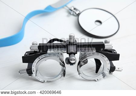 Trial Frame And Head Mirror On White Wooden Table, Closeup