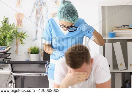 Dermatovenerologist Doctor Examining Skin On Buttocks Of Male Patient Using Magnifying Glass