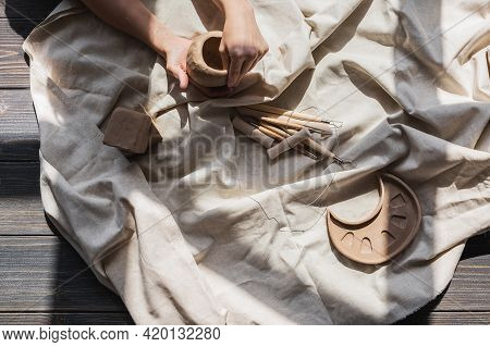 A Close-up View Of Clay Plates And A Paint Brush On A Wooden Table And Dried Flowers On A Background