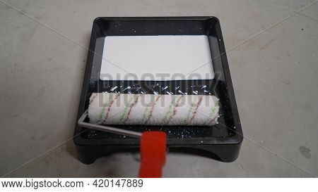 The Roller Is Immersed In A Tub With A White Primer. The Paint Roller Is Immersed In A White Primer 