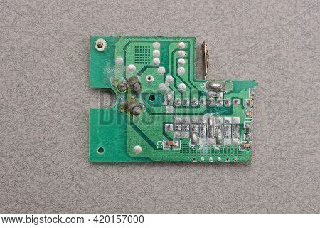 One Green Old Plastic Microcircuit With Lead Soldering Lies On A Gray Table