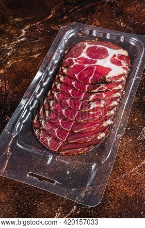 Italian Sliced Cured Coppa Meat In Vacuum Packaging. Dark Background. Top View