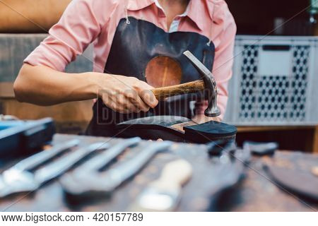 Close-up of woman shoemaker repairing some shoes