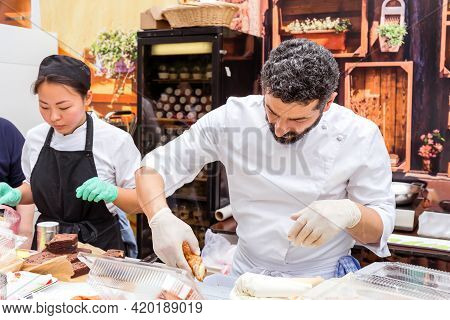 Moscow, Russia, July 13, 2019: An Italian Chef In Uniform Fills A Cream Cone With Cannoli Siciliani.