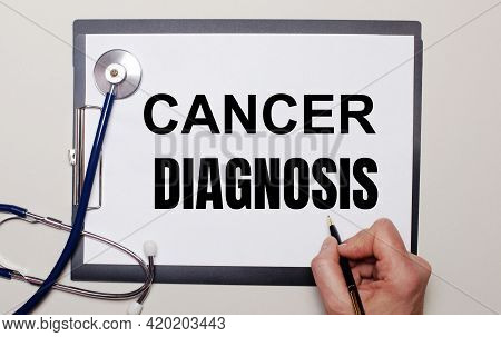 On A Light Background, A Stethoscope And A Sheet Of Paper, On Which A Man Writes Cancer Diagnosis. M