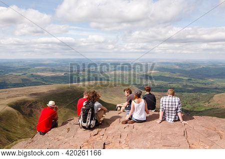 Brecon Beacons, Uk - April 25, 2011. Mixed Group Of Young Caucasian People, Hikers Sitting On The Pe