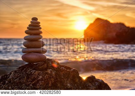 Concept of balance and harmony. Cairn stack of stones pebbles cairn on the beach coast of the sea in the nature on sunset. Meditative art of stone stacking