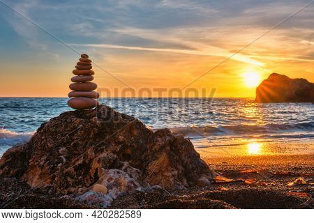 Concept of balance and harmony. Cairn stack of stones pebbles cairn on the beach coast of the sea in the nature on sunset. Meditative art of stone stacking