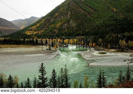 The Confluence Of Two Mountain Rivers In The Taiga At The Foot Of A High Hill.