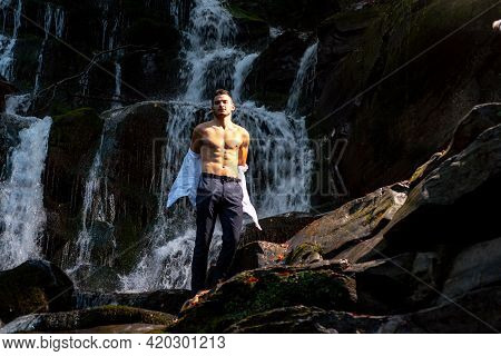 Muscular Man Going To Swim In Waterfall Water. Profit Business Concept. Businessman Undressing At Wa