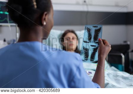 Close Up Of Asisstant With Black Skin Explaining Lungs Radiography To Sick Woman