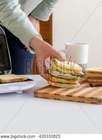 Hands Hold Cooked Fresh Sandwich With Cheese, Bacon And Vegetable Near Toster And Cup Of Coffee