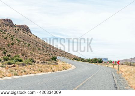 National Road N1 At Three Sisters In The Northern Cape Karoo. A Vehicle And Road Signs Are Visible