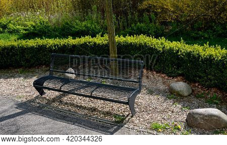 Gray Metal Park Bench With Transparent Design Of Metal Wires Cross Bars Path In The Park Flowerbed I