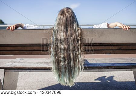 Brunette Preteen Girl With Blue Color Highlights Sitting On The Bench On The Bridge And Looking At R