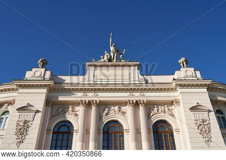 Facade Top Of The Main Building Of Warsaw University Of Technology On Blue Sky Background With Flyin