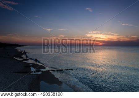 Sunset Over The Seashore - People Are Walking On The Beach
