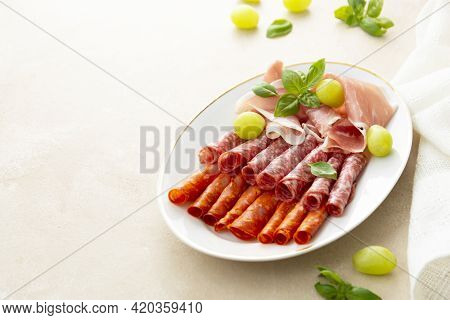 Meat Assortment, Salami Slices In Plate Decorated With Basil, Copy Space For Text.