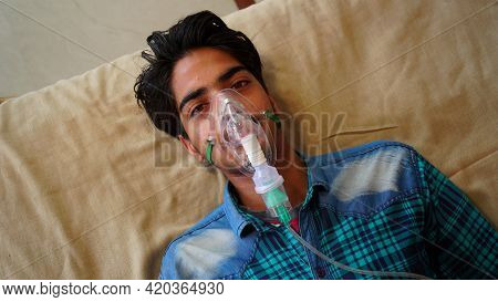 Young Boy Infected With Covid 19 Disease. Patient Inhaling Oxygen Wearing Mask With Liquid Oxygen Fl