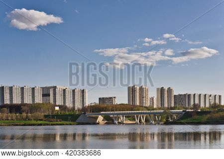 Beautiful Calm Urban Cityscape At Summer Day. View On Lake, Park, Road Bridge, Residential Buildigs 