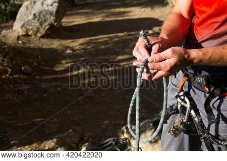 A Male Climber Ties A Safety Knot Eight On The Harness Before Climbing The Track. Climbing Equipment